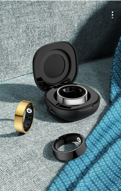 Aura smart ring in gold and black with charging case on textured fabric background
